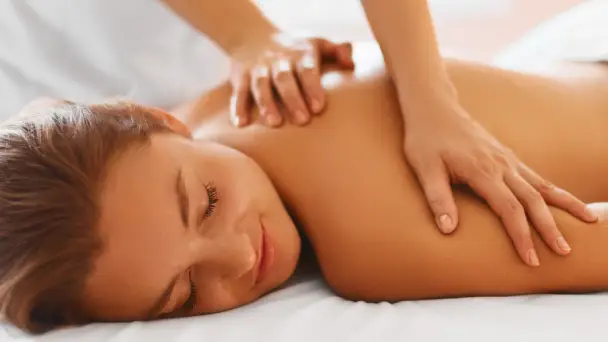 service-01-webp A person receives a relaxing massage, with one hand kneading the shoulder and upper back against a soft, blurred background.
