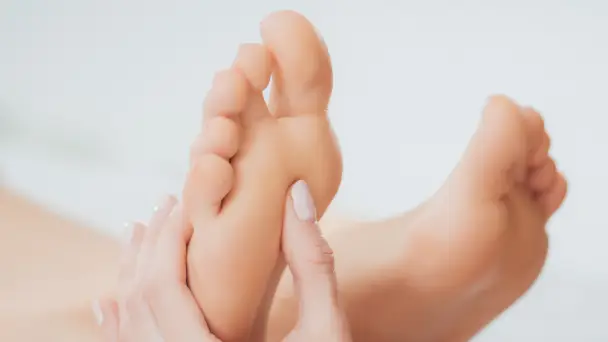 service-02 webp A close-up of a person receiving a foot massage, focusing on the hands gently applying pressure to the sole of a foot.